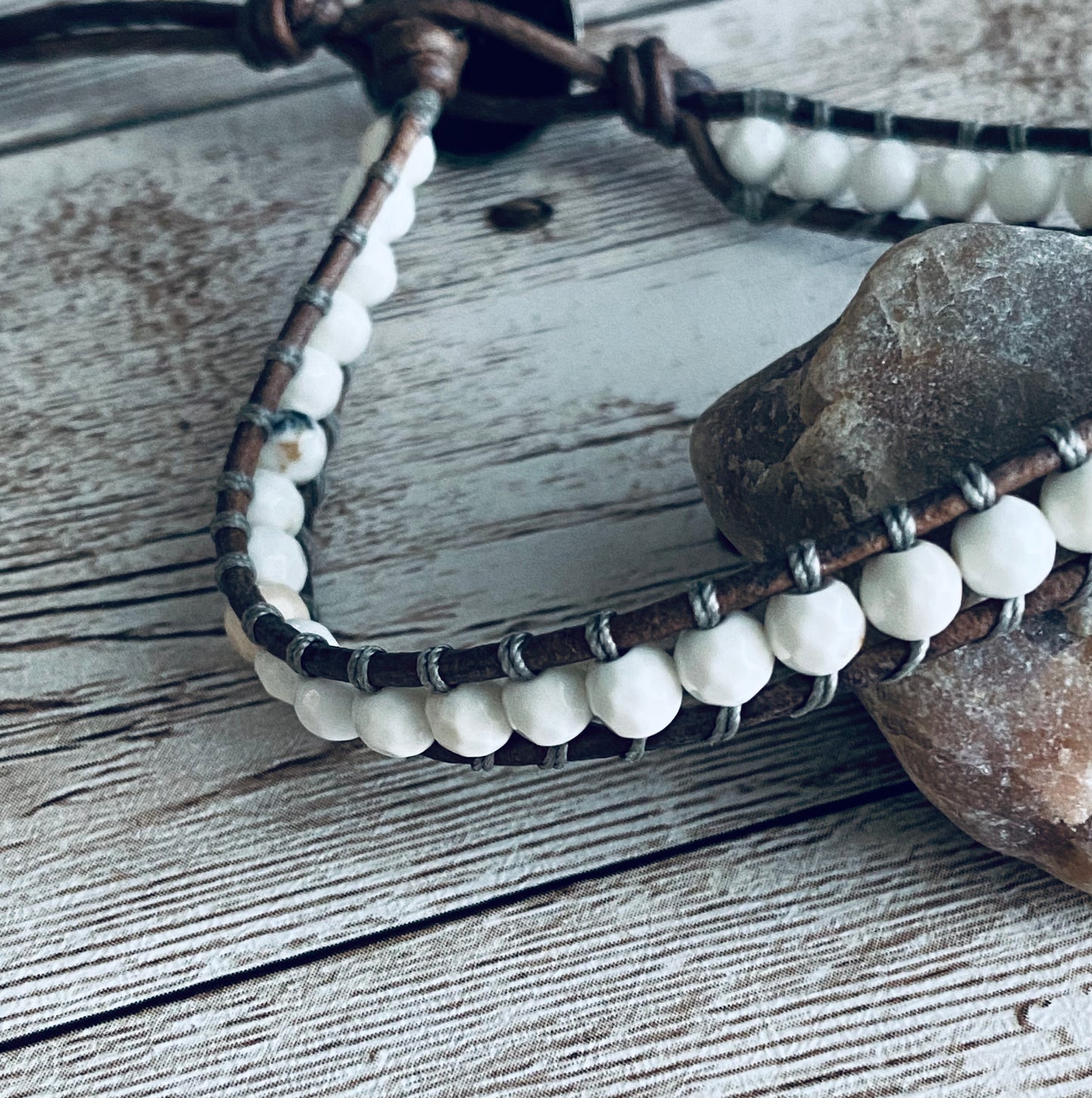 Single wrap bracelet with white beads and gray leather cord.