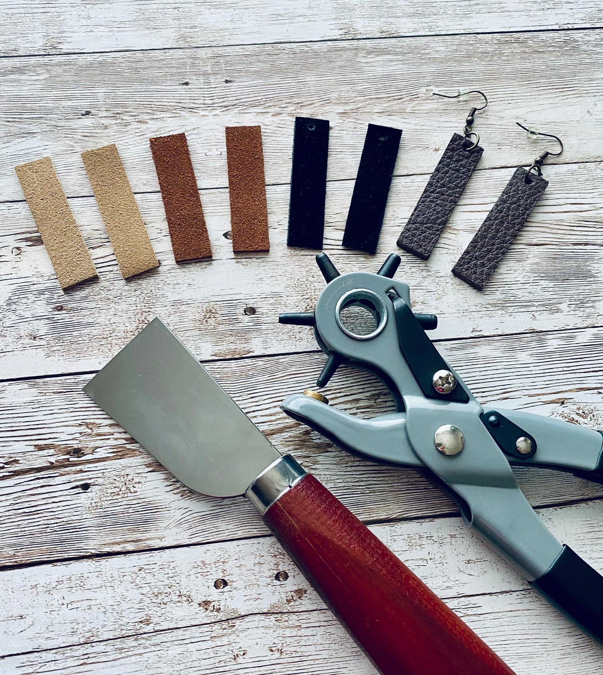 Crafting tools and earring materials on a wooden surface.